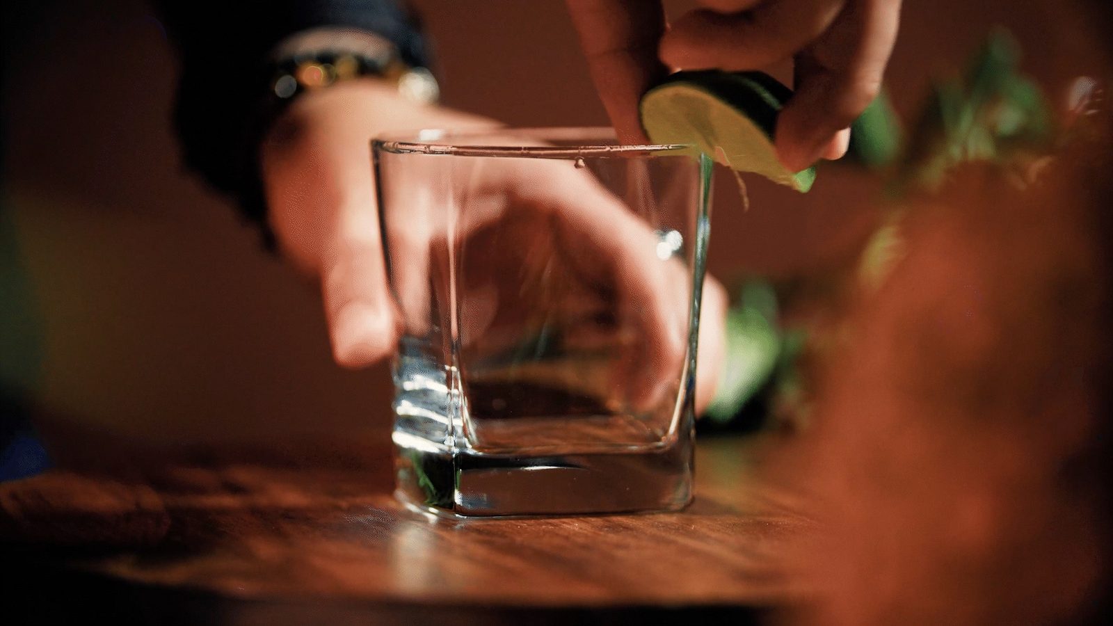 Manos exprimiendo limón sobre un vaso